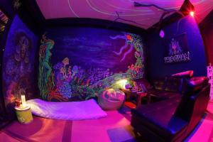 una camera con un letto in una stanza con luci viola di Tripovali Guesthouse a Ko Phangan