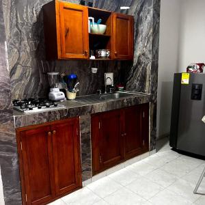 cocina con armarios de madera, fregadero y nevera en Apartamentos San José, en Cartagena de Indias