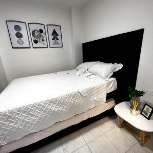 Un dormitorio con una gran cama blanca y una mesa en Apartamentos San José, en Cartagena de Indias