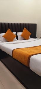 Una cama con almohadas naranjas y blancas. en HOTEL THE AVENUE, en Gamhāria