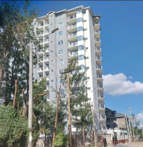 a tall white building with trees in front of it at LaMeg furnished 1 bedroom Garden Estate in Nairobi