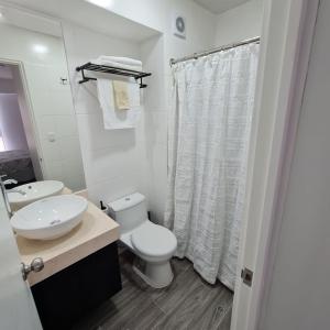 a white bathroom with a toilet and a sink at Departamento bajada a la playa in Lima