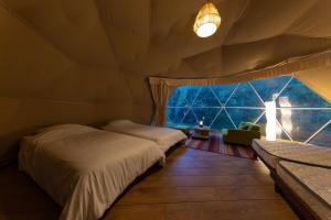 a bedroom with two beds and a large window at glampark Shikisou Shimane in Izumo