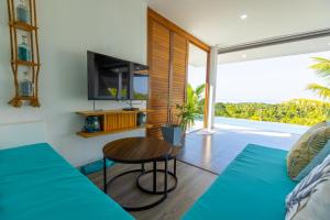 a living room with a table and a tv at Shades of Blue in Srithanu