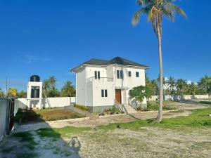 una casa blanca con una palmera delante de ella en Tropical Gem: 3-BR Beach Villa, en Pingwe