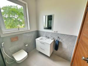 La salle de bains est pourvue d'un lavabo, de toilettes et d'une fenêtre. dans l'établissement Tropical Gem: 3-BR Beach Villa, à Pingwe