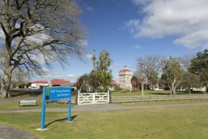 a sign in a park with a water tower in the background at Maple Lodge Motel in Matamata
