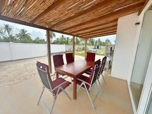 uma mesa de madeira e cadeiras num pátio em Tropical Gem: 3-BR Beach Villa em Pingwe