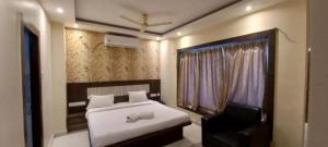 a bedroom with a white bed and a television at Goroomgo Hotel Home Town Near Golden Beach Puri in Puri