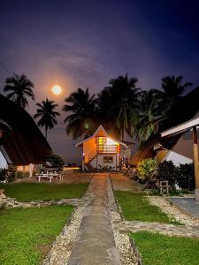 Una casa de noche con la luna en el cielo en Surya Beach Resort Palawan en Aborlan