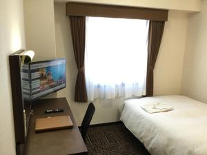 高山市にあるホテルアルファーワン高山バイパスのベッド、デスク、テレビが備わるホテルルームです。