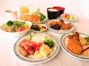 高山市にあるホテルアルファーワン高山バイパスの食べ物の皿が置かれた白いテーブル