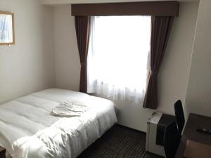 a bedroom with a white bed and a window at Hotel Alpha-One Takayama Bypass in Takayama