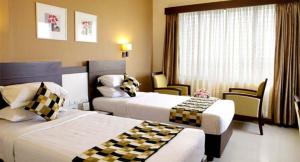 ein Hotelzimmer mit 2 Betten und einem Fenster in der Unterkunft Cochin Seaport Hotel in Kochi