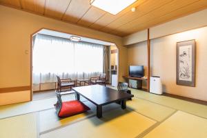 un soggiorno con tavolo, sedie e TV di Hotel Ichii a Kusatsu