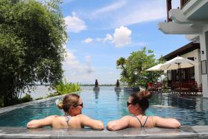 zwei Frauen im Pool eines Resorts in der Unterkunft Nghê Prana Villa & Spa Hoi An in Hoi An