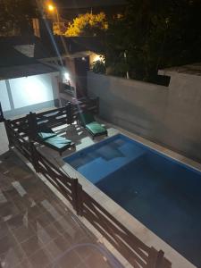 una piscina por la noche con 2 sillas verdes en Departamento Genaro en Mina Clavero