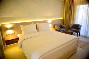 een hotelkamer met een wit bed en een stoel bij Reef Oasis Beach Aqua Park Resort in Sharm El Sheikh
