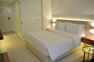 Reef Oasis Beach Aqua Park Resort في شرم الشيخ: غرفة نوم بسرير ابيض كبير مع مخدات بيضاء