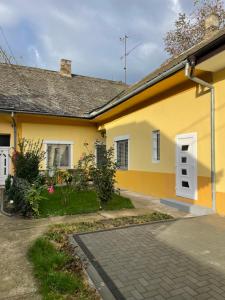 a yellow house with a white door and a driveway at IGNIM Apartment in Subotica