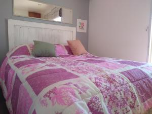 Una cama con una manta púrpura y almohadas. en Pensamientos del alma (Uribelarrea) en Uribelarrea