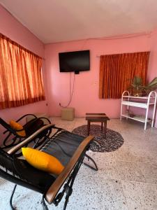 sala de estar con paredes de color rosa y TV de pantalla plana. en Hotel El almirante, en Tecolutla