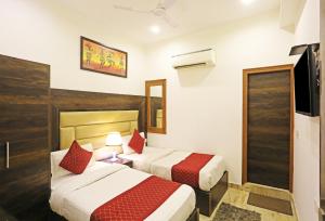 a hotel room with two beds and a tv at Hotel De Kiara Near Delhi Airport in New Delhi