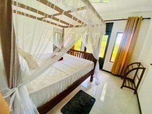 - une chambre avec un lit et une moustiquaire dans l'établissement Aura, à Unawatuna