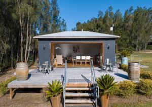 Casa con terraza con sillas y mesa en Sweetacres Hunter Valley en Pokolbin