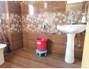 uma casa de banho com um lavatório e uma lata de lixo vermelha em The Mountain Paradise Hotel, Rewalsar, H.P. em Mandi