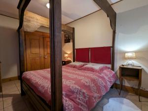 ein Schlafzimmer mit einem Himmelbett mit einer roten Bettdecke in der Unterkunft Gîte Corcieux, 3 pièces, 4 personnes - FR-1-589-36 in Corcieux