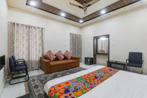 a bedroom with a bed and a couch and a television at FabHotel Sarovar Palace in Muthiganj