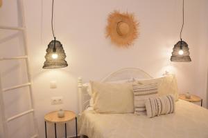a bedroom with a white bed with three lights at Patmos Little Suites in Skala