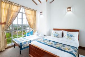 a bedroom with two beds and a large window at Aaradhya Nuwara Eliya in Nuwara Eliya