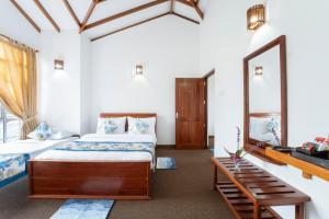 a bedroom with two beds and a mirror at Aaradhya Nuwara Eliya in Nuwara Eliya