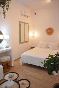 1 dormitorio con cama blanca y mesa en Patmos Little Suites, en Skala