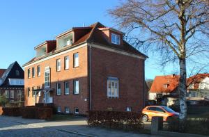a brick building with a car parked in front of it at Haus Auguste, Strandlaeufer in Warnemünde