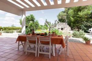 een tafel en stoelen op een patio bij Villa Menhir with pool garden and tennis - Happy Rentals in Tuglie