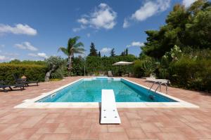 een zwembad met een bank in het midden bij Villa Menhir with pool garden and tennis - Happy Rentals in Tuglie