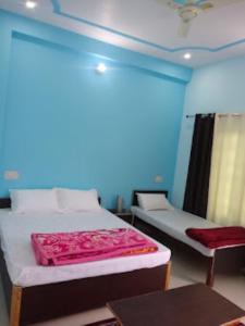 two beds in a room with a blue wall at Hotel Vikram Palace Sapeta in Barkot