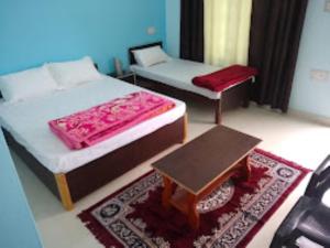 a bedroom with two beds and a table in it at Hotel Vikram Palace Sapeta in Barkot