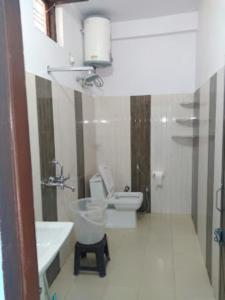 a white bathroom with a toilet and a sink at Hotel Vikram Palace Sapeta in Barkot