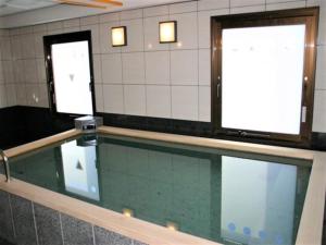 a swimming pool in a bathroom with two windows at Hotel Alpha-One Tsuyama in Tuyama