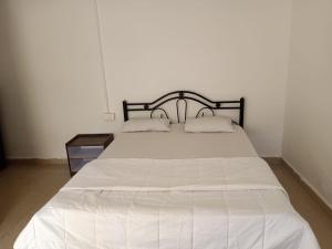 a bedroom with a white bed with a black headboard at Royal Touch Beach Huts in Palolem