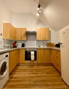 cocina con armarios de madera, lavadora y secadora en Central Crewe - Modern 1BR Haven, en Crewe