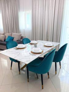 a dining room table with blue chairs and a white at Lux High Rise Marina Apartment in Dubai