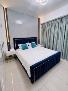 a bedroom with a large bed with blue pillows at Lux High Rise Marina Apartment in Dubai
