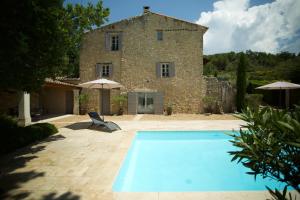 ein Haus mit einem Pool vor einem Gebäude in der Unterkunft La Petite Paradisse – mas provençal exceptionnel in Blauvac