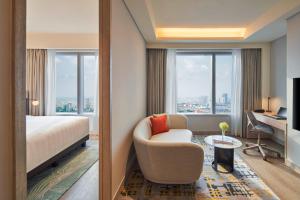 una camera d'albergo con letto, sedia e scrivania di PARKROYAL Serviced Suites Jakarta a Giacarta