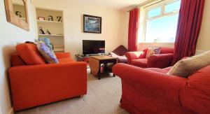 a living room with two red chairs and a television at Self-catering Lighthouse Keeper's Cottage on the NC500 in Wick